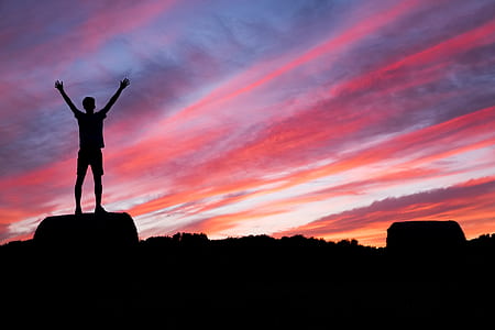 silhouette of person standing on rock during sunset thumbnail