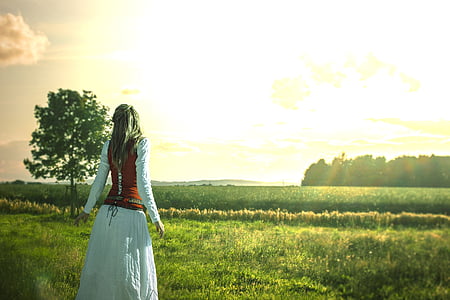 woman wearing white and red long-sleeved dress standing on green grass thumbnail