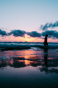 man walking on shoreline during golden hour thumbnail