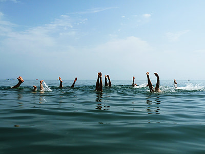 group of person swims with feet on top under blue sky thumbnail