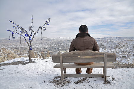 person wearing jacket seating on gray bench during daytime thumbnail