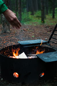 person standing beside black fire pit thumbnail