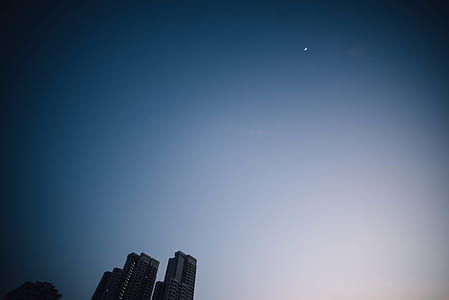 city buildings under blue sky with moon thumbnail