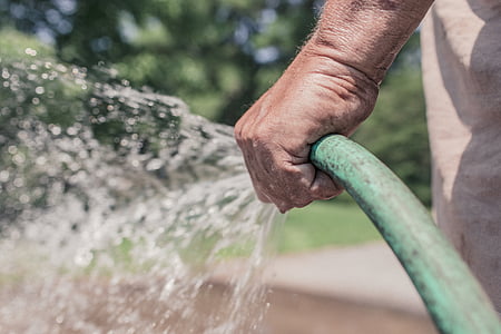 person holding green water hose thumbnail