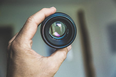 person holding camera lens thumbnail