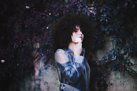 woman wearing blue cold-shoulder collard top holding white flower thumbnail