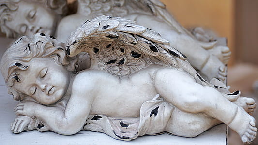selective focus photography of sleeping cherub figurine thumbnail