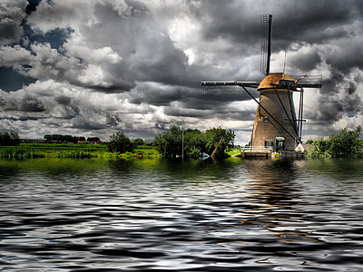 brown windmill near body of water under gray clouds during daytime thumbnail