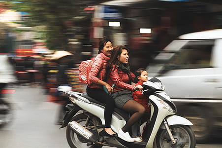 two women riding white motor scooter thumbnail