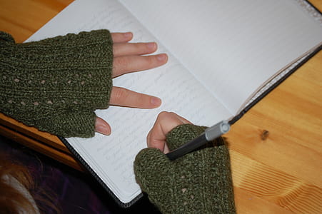 person in green long-sleeved shirt holding ballpoint pen thumbnail