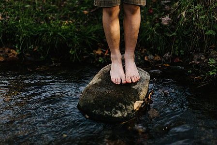 person stands on rock on body of water thumbnail