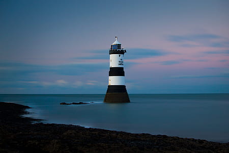 white and black lighthouse in the near of seashore thumbnail