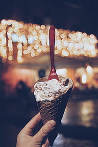 bokeh photography of person holding ice cream cone thumbnail