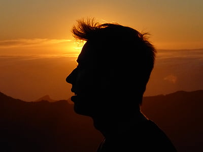 silhouette photo of man standing far from hill during golden hour thumbnail