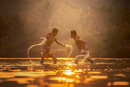 two men standing on body of water taken during sunset thumbnail