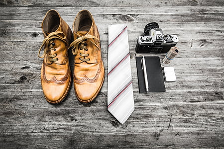 pair of brown leather shoes beside white and brown striped necktie and gray SLR camera thumbnail