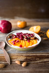 selective focus photography of peace slices, pomegranate seeds, and almond seeds dish thumbnail