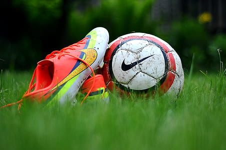 close-up photo of cleats and soccer ball on green grass thumbnail
