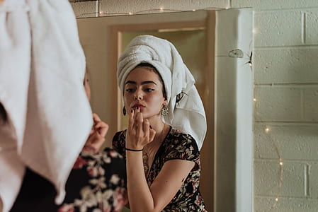 woman in front of mirror putting lipstick thumbnail
