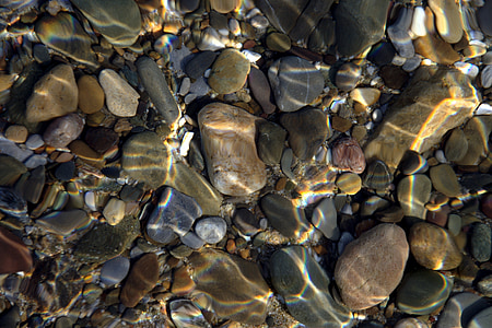 assorted-color stones under body of water thumbnail