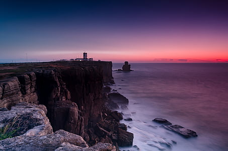 rock formation near body of water during sunset thumbnail