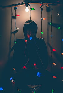 Man Sitting on Chair With Multi-colored String Lights thumbnail