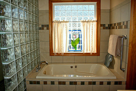 rectangular white enamel bathtub inside room with gray wall tiles thumbnail