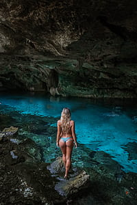 woman in cave standing on rock near river thumbnail