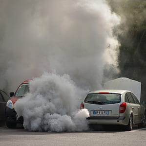 vehicle blowing smoke on parking area beside red car thumbnail
