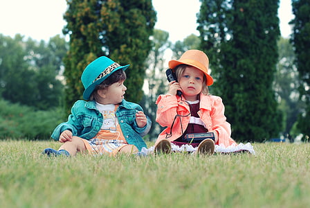 photo of girl wearing orange suit holding telephone near boy wearing teal jacket thumbnail