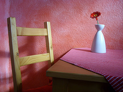 brown wooden table near chair with red daisy on white ceramic vase thumbnail