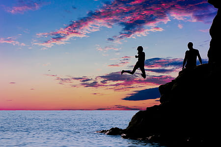 silhouette photo of man and woman on rock cliff during dawn thumbnail