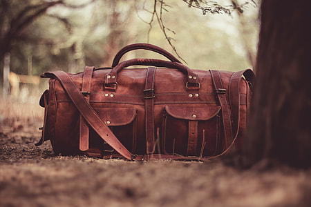 brown leather satchel duffel bag beside brown tree during daytime thumbnail
