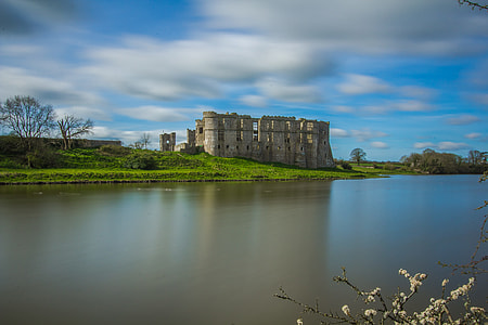 gray castle beside body of water under cloudy sky during time thumbnail