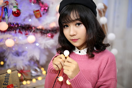 woman standing inside room beside Christmas tree thumbnail