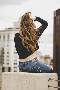 woman in black long-sleeved top and blue jeans sitting on concrete thumbnail