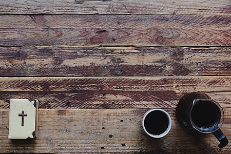 pitcher beside mug and Bible on brown surface thumbnail