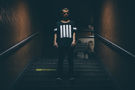 man wearing black and white shirt standing in the middle of stairs thumbnail