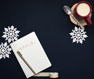 Brown Pen on White Notebook Near Red Coffee Mug and Silver Spoon on Top of Blue Surface thumbnail