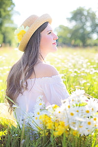 woman wearing white off-shoulder top and brown hat sitting on flower field thumbnail