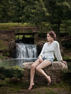 Woman Wearing White Long Sleeve Shirt Sitting Near Waterfalls thumbnail