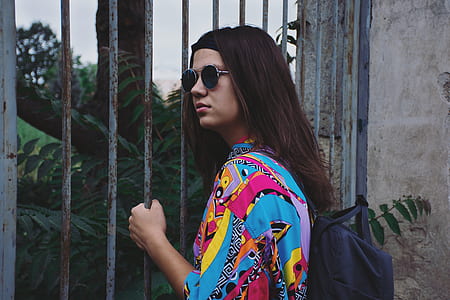woman in blue, red, and yellow top holding on metal rails thumbnail