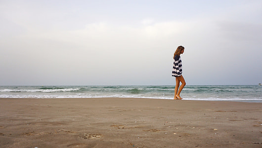 person in black and white striped mini dress walking near seashore thumbnail