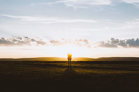 silhouette photography of person standing under sun rise thumbnail
