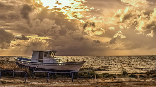 brown and white boat on sandy shore during sunset thumbnail