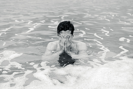 grayscale photo of man soaking in body of water thumbnail