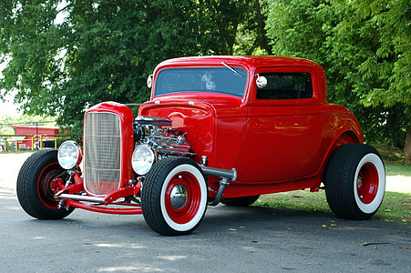 classic red vehicle on road near trees at daytime thumbnail
