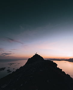 silhouette photography of rock formation near body of water thumbnail