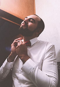Man in White Dress Shirt Tying a Red Bow Tie thumbnail