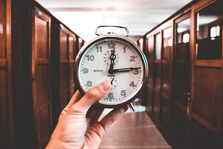 person holding round stainless steel alarm clock thumbnail